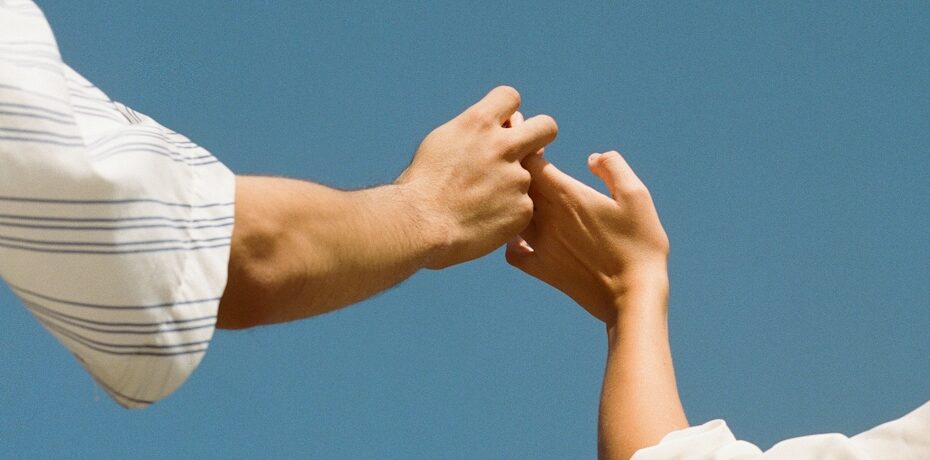 Symbolbild für Verbindung und Vertrauen – zwei Hände berühren sich vor blauem Himmel, fotografiert im Editorial-Stil für moderne Markenkampagnen.