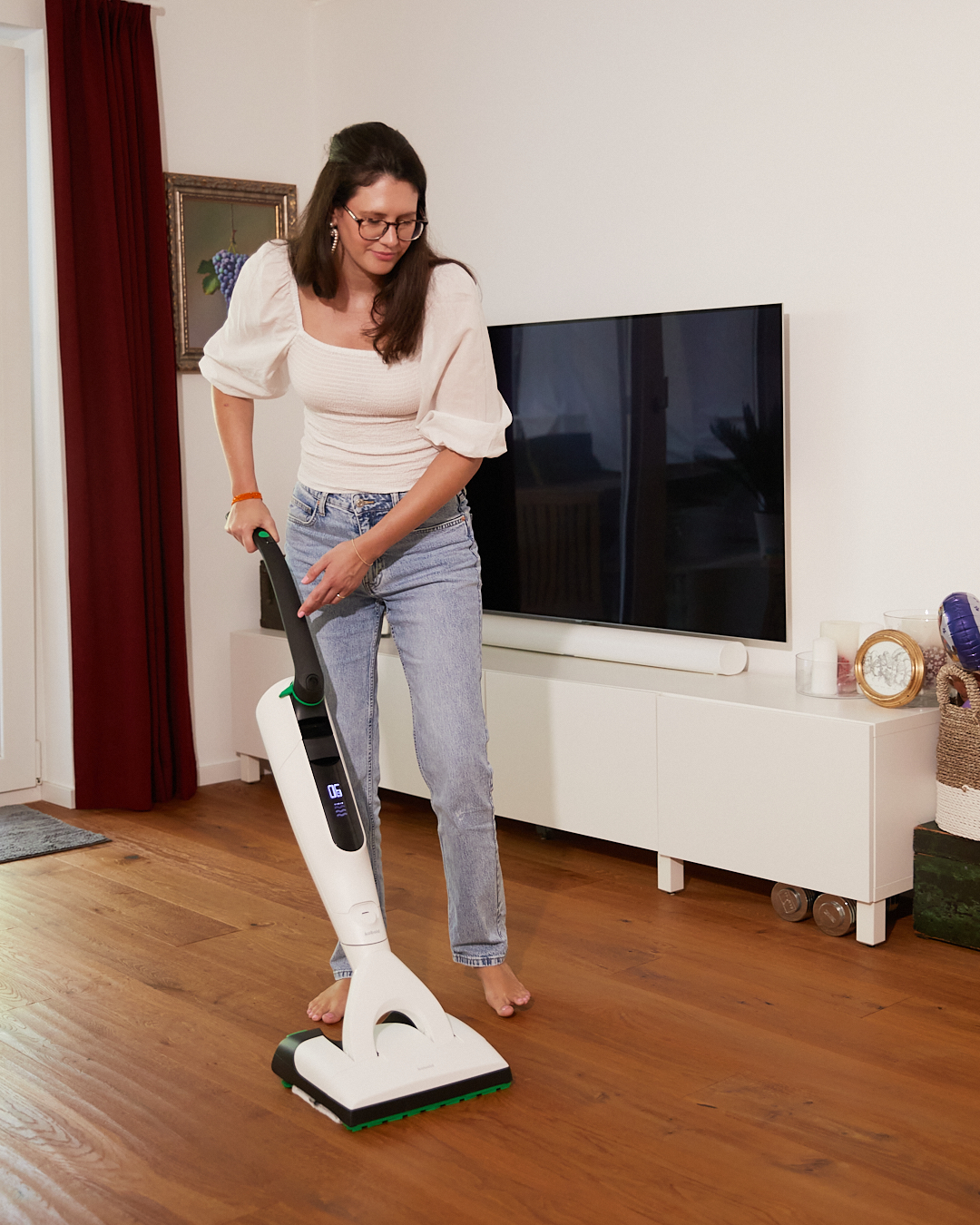 Bodenreinigung mit dem Kobold SP7 – Frau wischt barfuß den Holzboden in ihrem Wohnzimmer als Teil der aime Kampagne „Mental (un)load“ für Vorwerk.